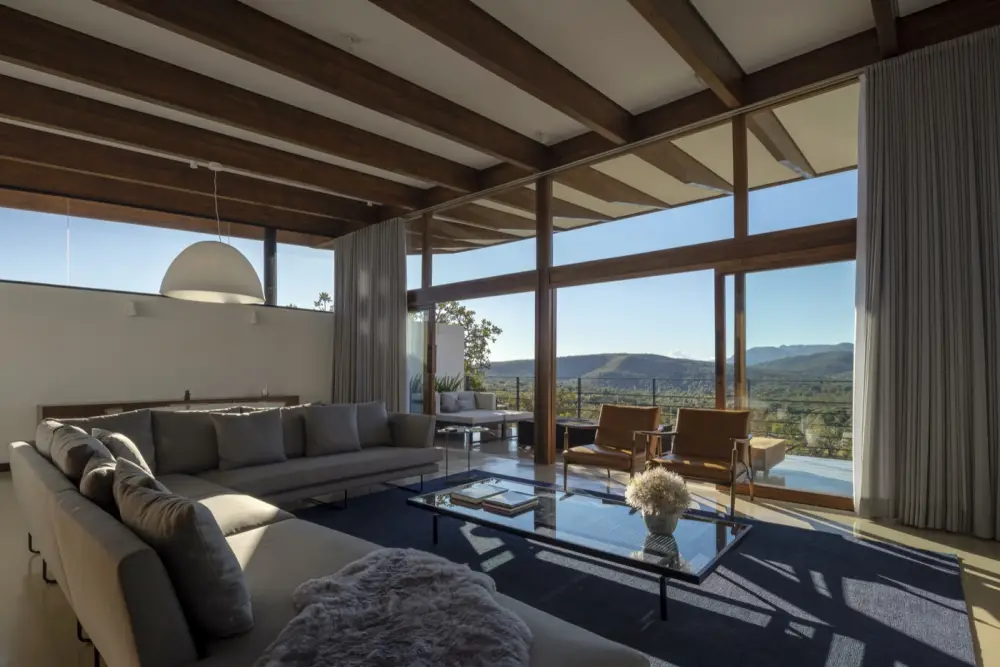 Sala de estar com vigas de madeira laminada colada e grandes vãos de vidro